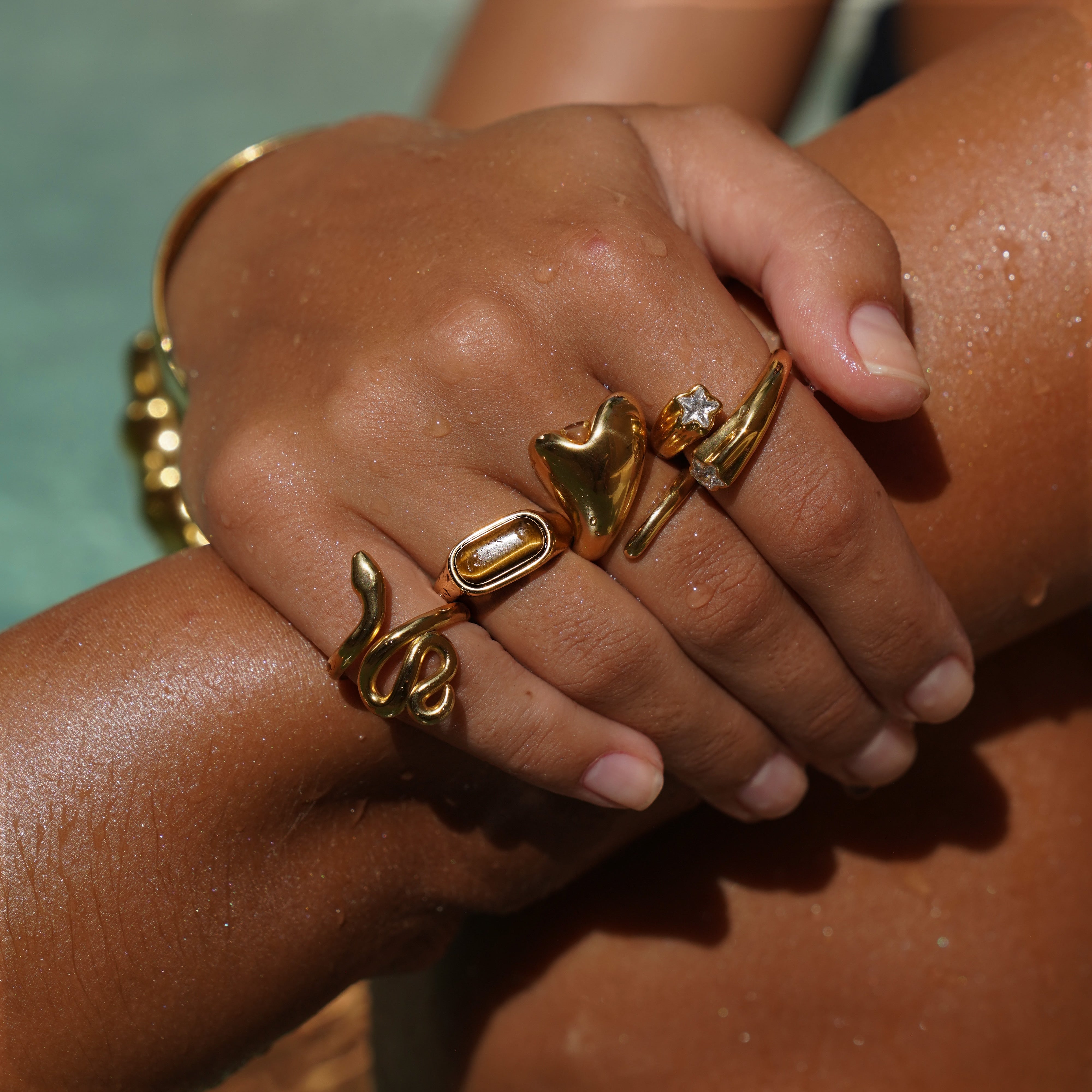 Close-up of hands with gold jewelry against a blurred background