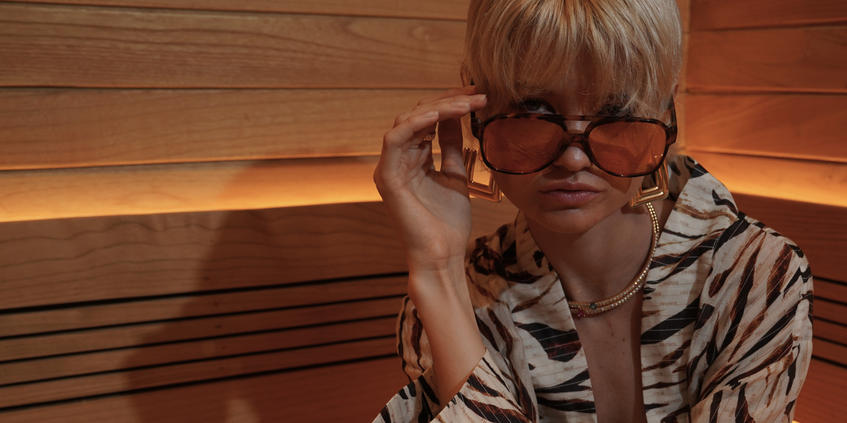 Person wearing a zebra print outfit and large sunglasses in a wooden room.