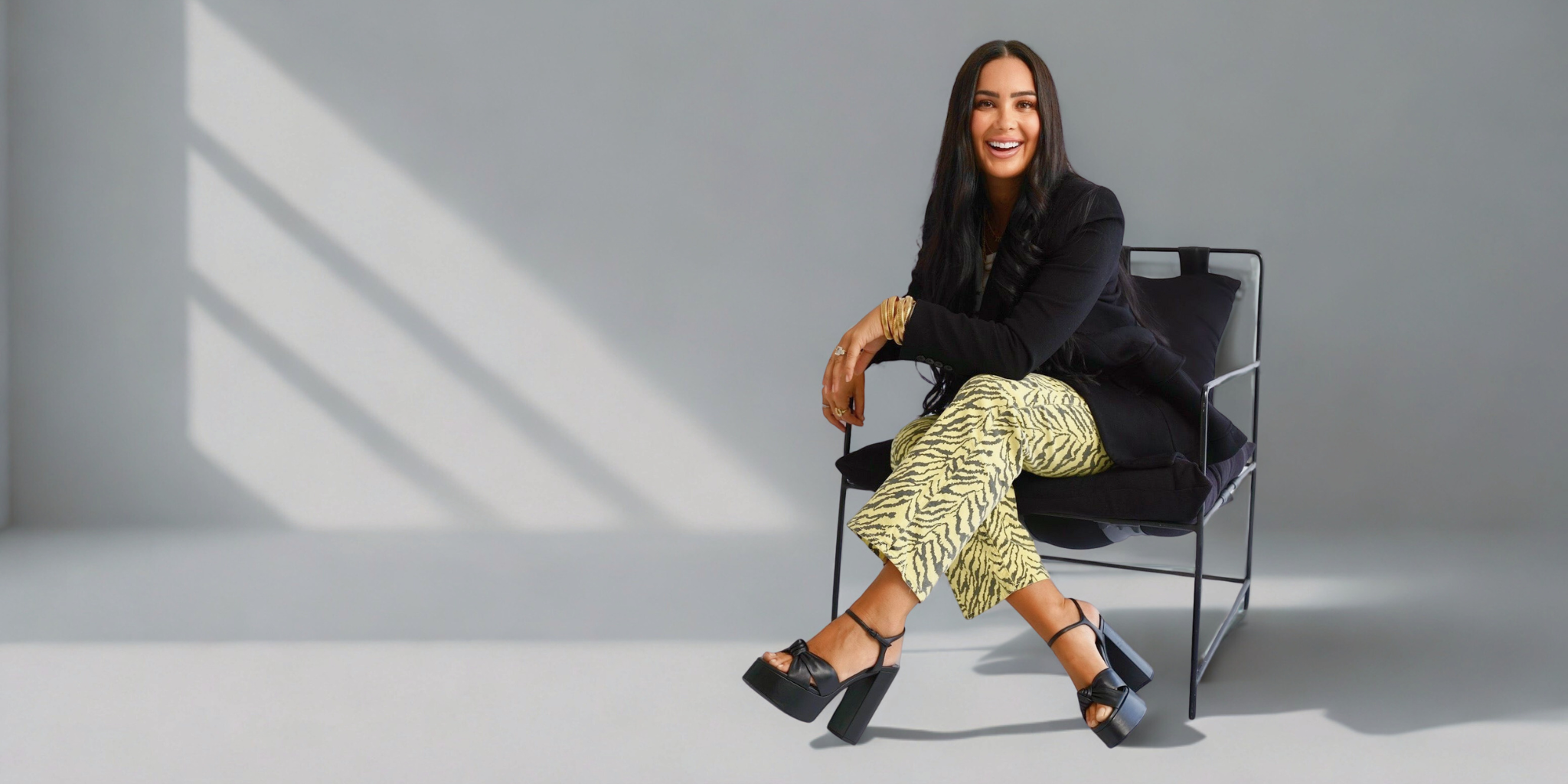 Woman sitting on a chair in a minimalistic setting with a gray background